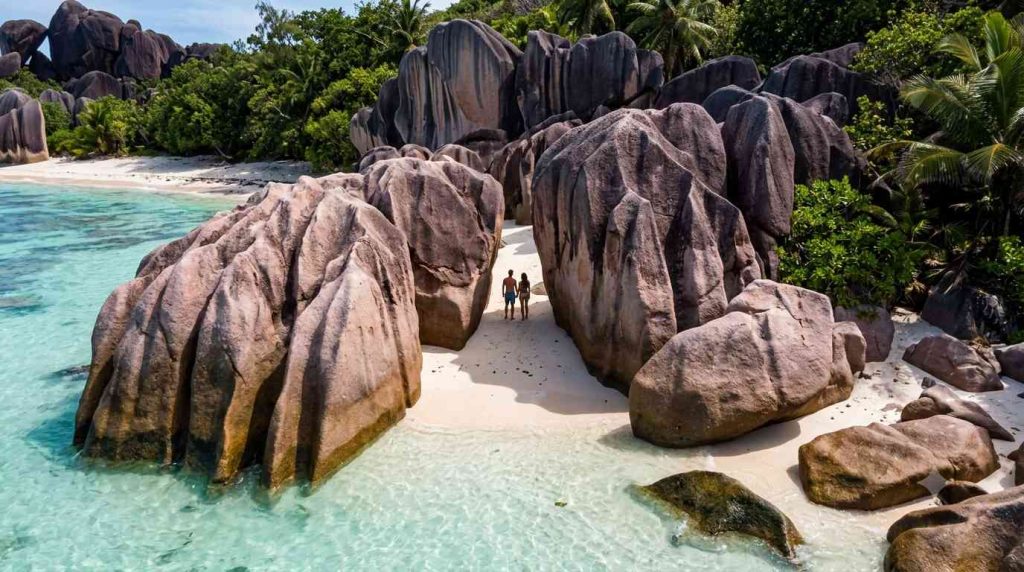 Couple between ancient granite boulders on Anse Source d'Argent beach La Digue Seychelles for luxury honeymoon