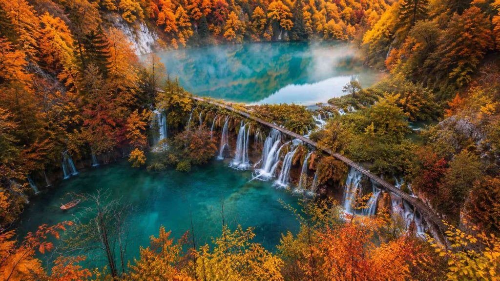 Wooden boardwalk over turquoise waterfall at Plitvice Lakes National Park Croatia in autumn