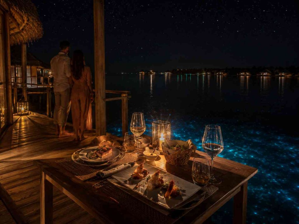 Private candlelit overwater dinner for two at night at Gili Lankanfushi with stars reflected in Maldives lagoon